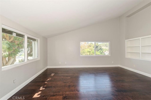 empty room featuring lofted ceiling, baseboards, and wood finished floors