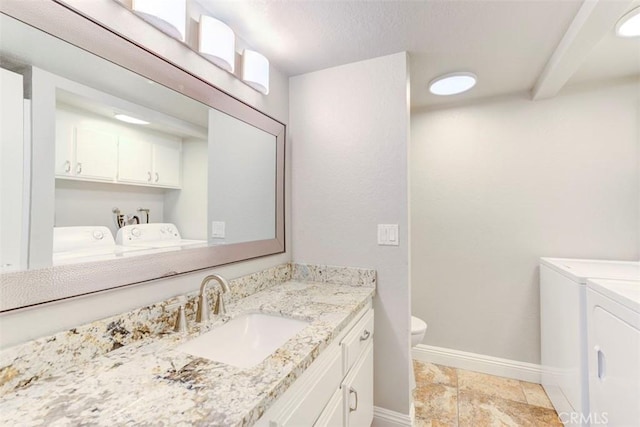 bathroom featuring vanity, baseboards, and washing machine and clothes dryer