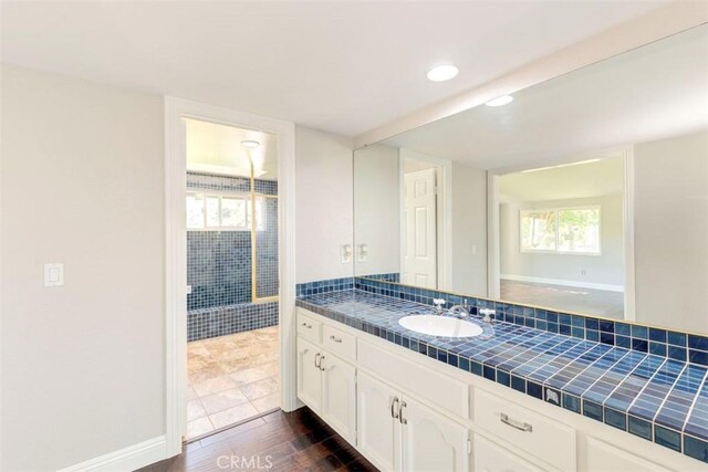 bathroom with recessed lighting, baseboards, wood finished floors, and vanity