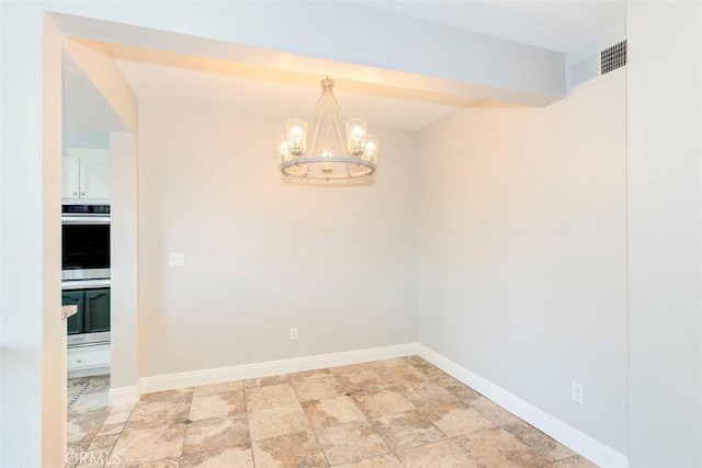 spare room with a chandelier, stone finish floor, visible vents, and baseboards