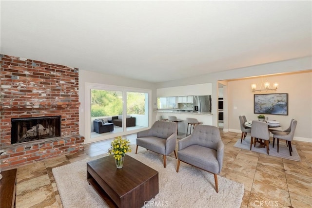 living room with a brick fireplace, baseboards, and a notable chandelier