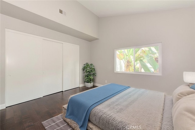 bedroom with a closet, visible vents, baseboards, and wood finished floors