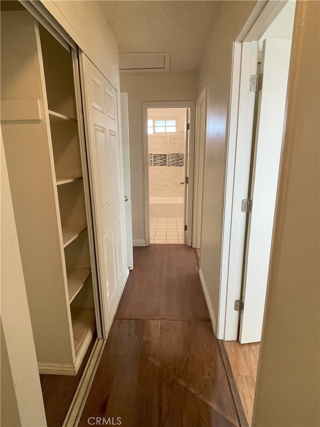 hallway with dark hardwood / wood-style flooring and a textured ceiling