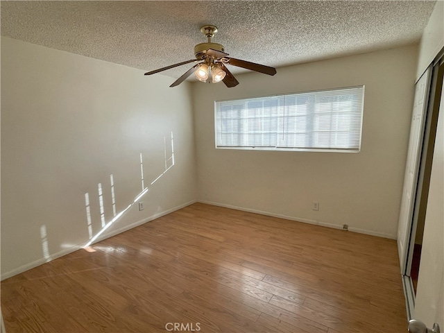 empty room with ceiling fan, light hardwood / wood-style flooring, and a textured ceiling