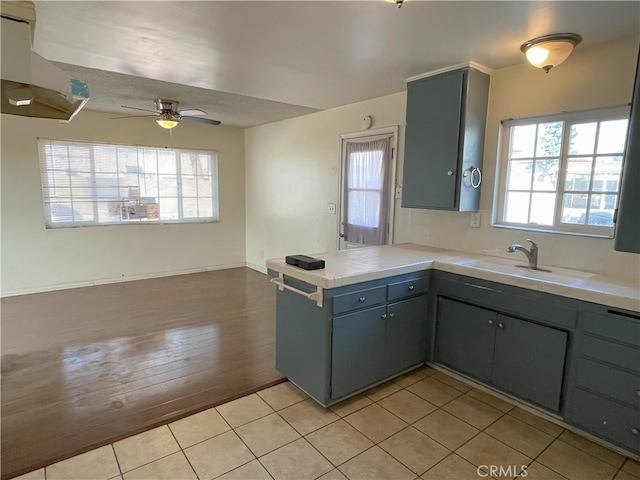 kitchen with ceiling fan, light tile patterned floors, sink, and kitchen peninsula