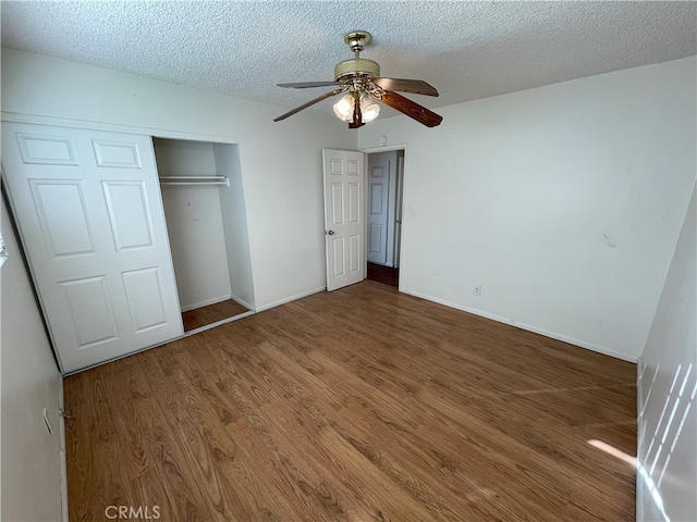 unfurnished bedroom with ceiling fan, dark wood-type flooring, a textured ceiling, and a closet