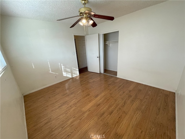 unfurnished bedroom with a textured ceiling, a closet, hardwood / wood-style flooring, and ceiling fan