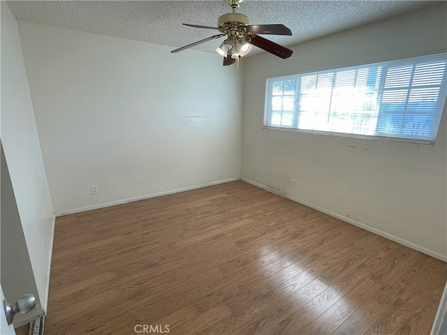 empty room featuring ceiling fan, wood-type flooring, and a textured ceiling