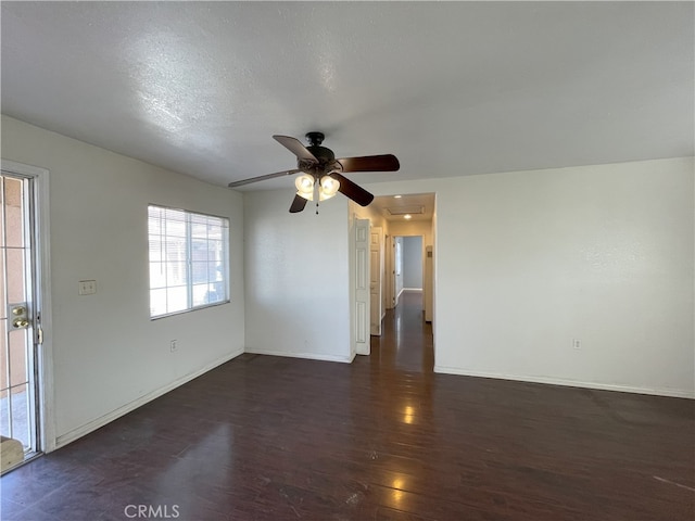 empty room with ceiling fan, dark wood-type flooring, and a textured ceiling