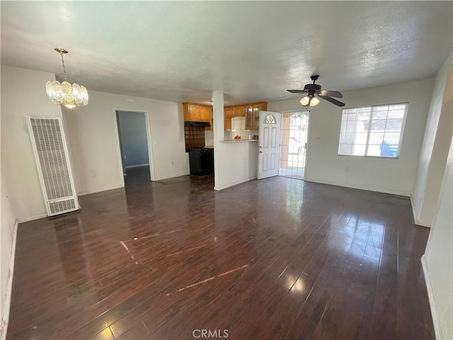 unfurnished living room with ceiling fan with notable chandelier, dark hardwood / wood-style floors, and a textured ceiling