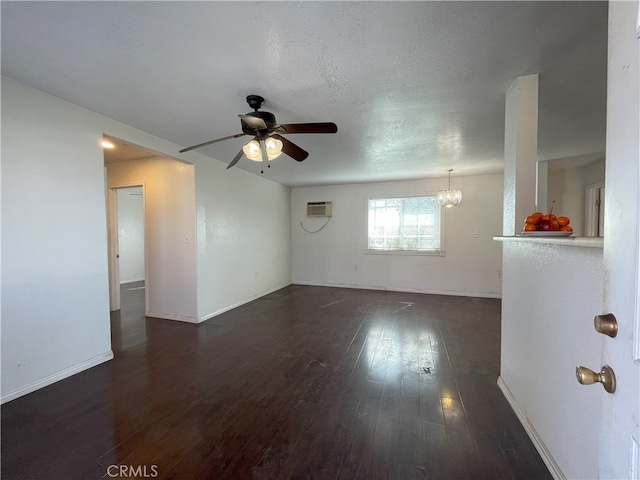 empty room with ceiling fan with notable chandelier, dark wood-type flooring, and a wall mounted AC