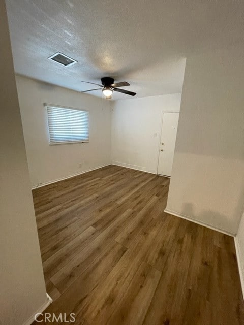 spare room with ceiling fan, a textured ceiling, and dark hardwood / wood-style flooring