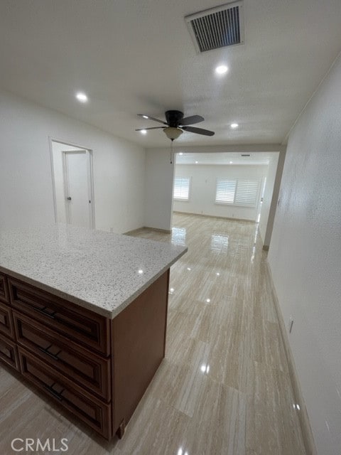 kitchen featuring ceiling fan and light stone countertops