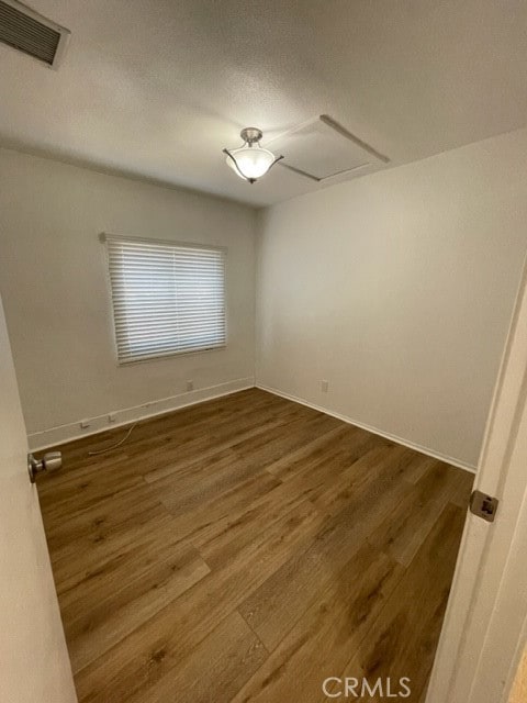 spare room with a textured ceiling and dark hardwood / wood-style floors