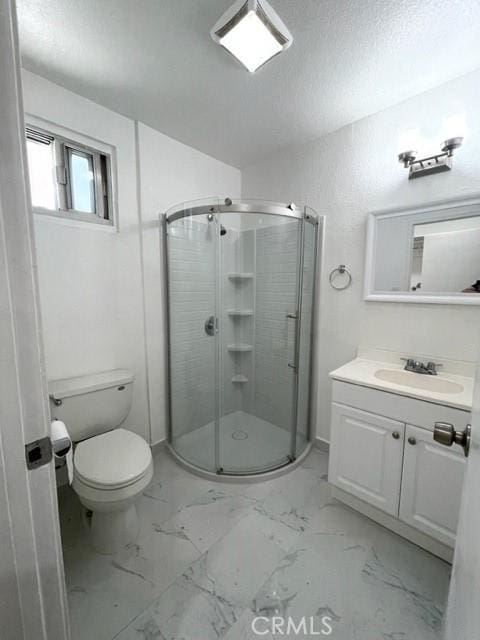 bathroom with marble finish floor, toilet, vanity, and a stall shower