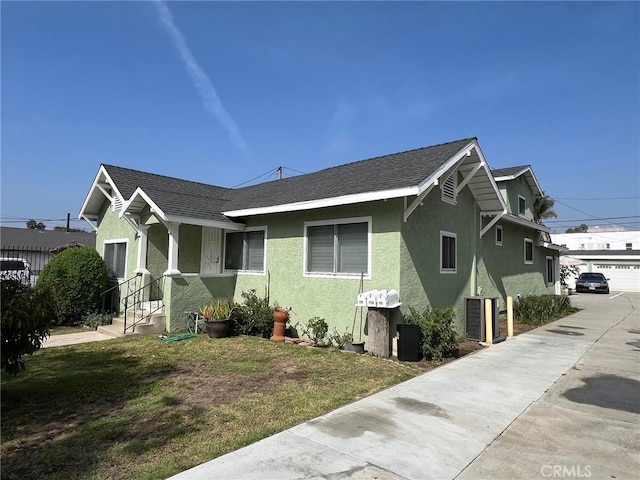 view of home's exterior featuring stucco siding, a yard, and a shingled roof