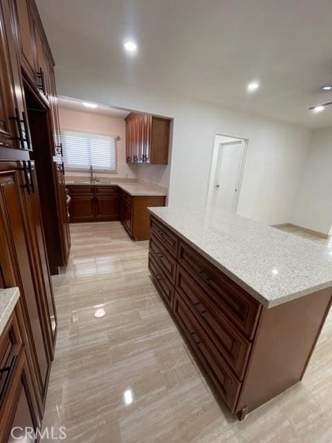 kitchen featuring recessed lighting, light stone countertops, and a sink