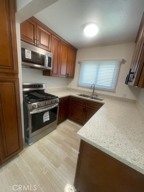 kitchen featuring stainless steel appliances, light stone countertops, sink, and a textured ceiling