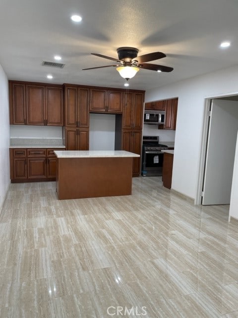 kitchen with a center island, appliances with stainless steel finishes, and ceiling fan