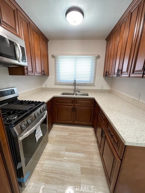 kitchen with sink, appliances with stainless steel finishes, and a textured ceiling