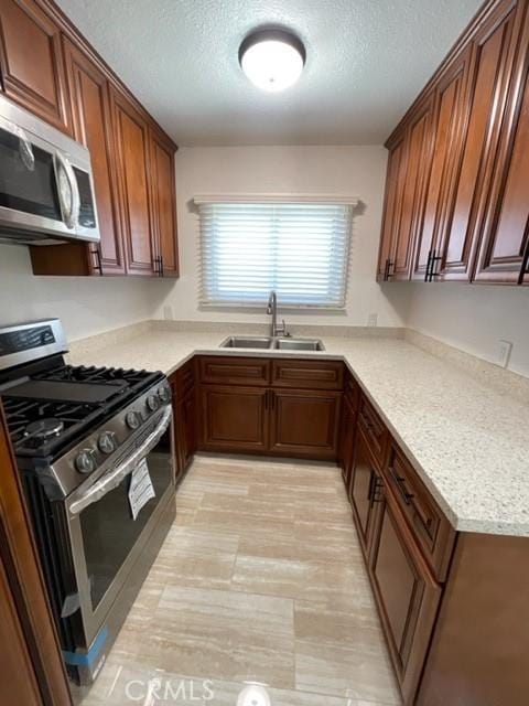 kitchen with light countertops, a textured ceiling, appliances with stainless steel finishes, and a sink