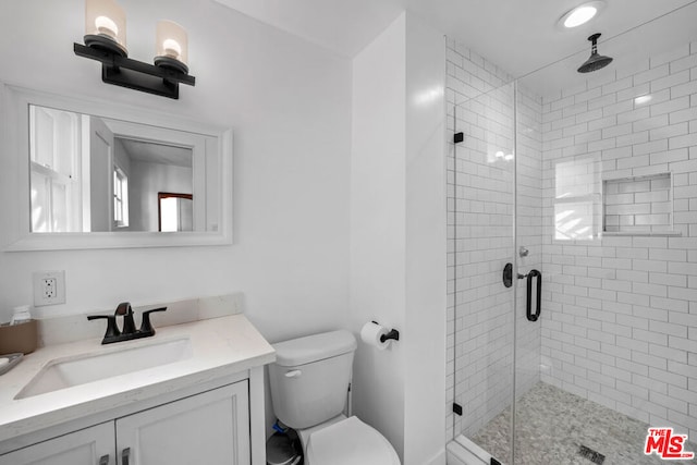 bathroom with walk in shower, vanity, and toilet