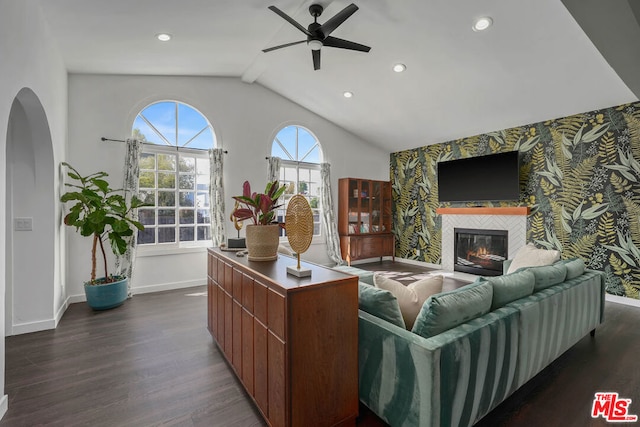 living room with ceiling fan, lofted ceiling, a tiled fireplace, and dark hardwood / wood-style flooring