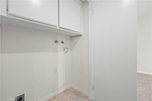 interior space featuring electric dryer hookup, hookup for a washing machine, light colored carpet, and cabinets