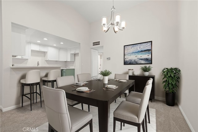 carpeted dining room with high vaulted ceiling, a notable chandelier, and sink