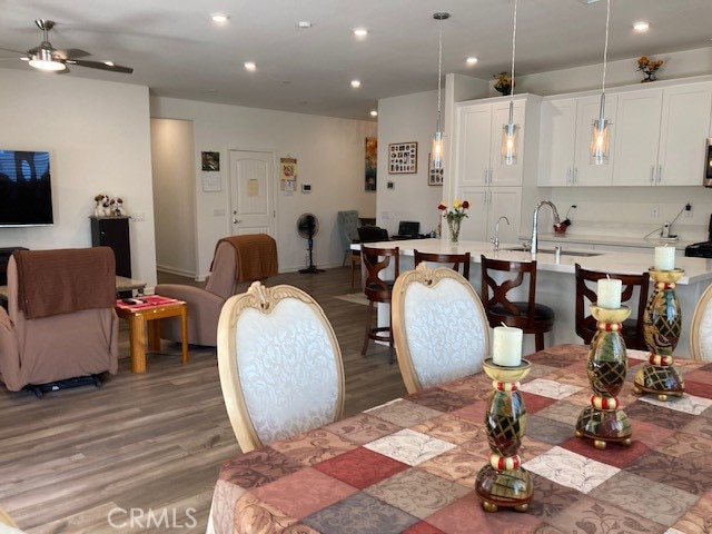 dining space featuring dark wood-type flooring, ceiling fan, and sink