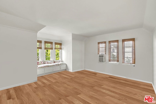 spare room featuring cooling unit, light hardwood / wood-style floors, and a healthy amount of sunlight