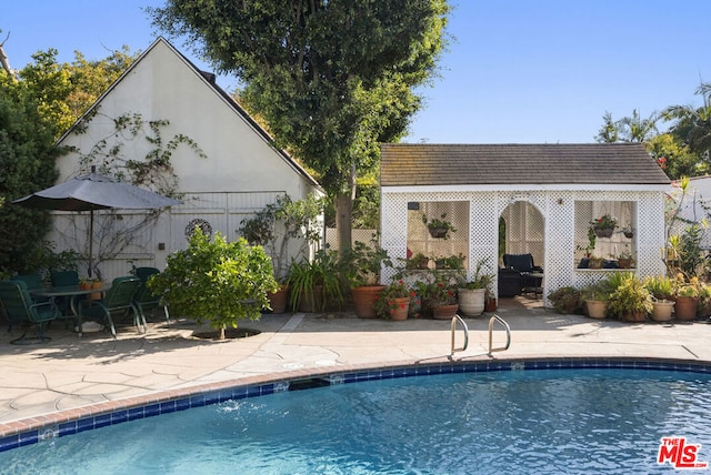 view of pool with an outbuilding and a patio area