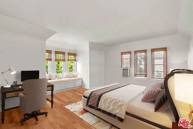 bedroom featuring cooling unit, vaulted ceiling, light hardwood / wood-style floors, and multiple windows