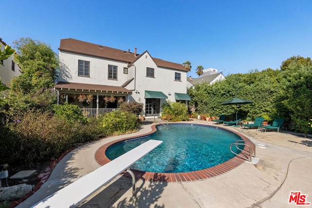 view of swimming pool featuring a patio and a diving board