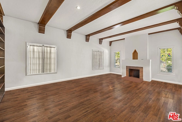 unfurnished living room with a brick fireplace, dark hardwood / wood-style floors, beam ceiling, and a healthy amount of sunlight