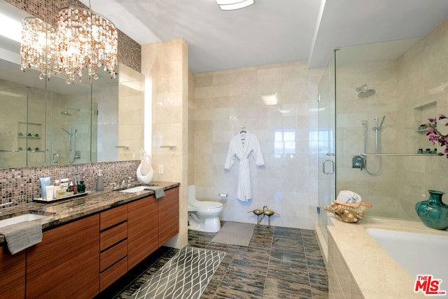 bathroom with tile walls, decorative backsplash, a shower with shower door, vanity, and toilet