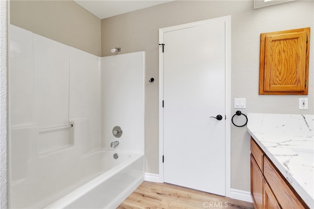 bathroom featuring wood-type flooring, tub / shower combination, and vanity