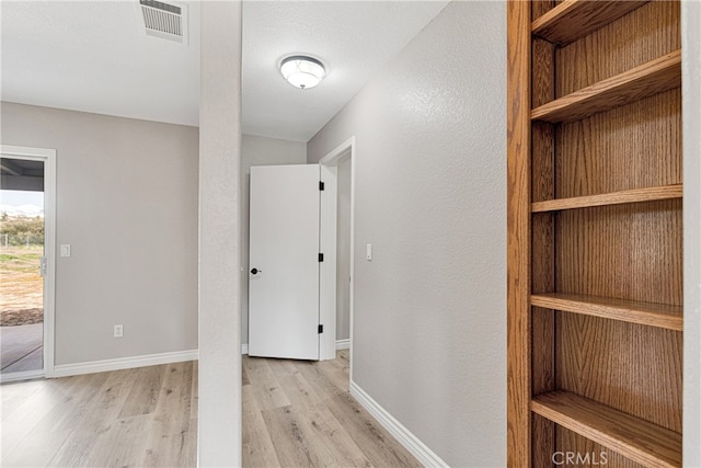 hall featuring light wood-type flooring and a textured ceiling