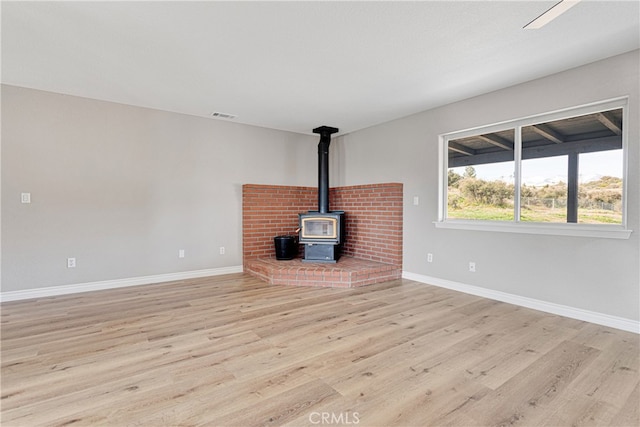 unfurnished living room featuring light hardwood / wood-style flooring and a wood stove