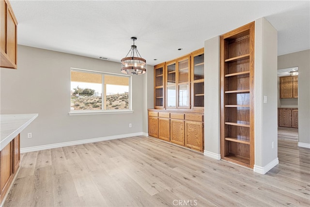 unfurnished living room featuring a textured ceiling, light hardwood / wood-style flooring, and a notable chandelier