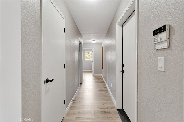 hall with a textured ceiling and light hardwood / wood-style floors