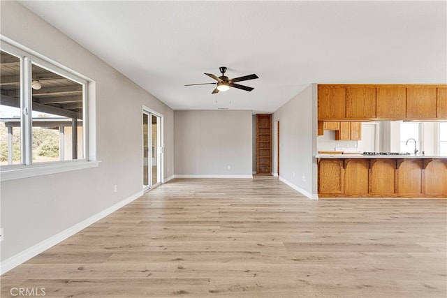 unfurnished living room with light wood-type flooring, sink, and ceiling fan