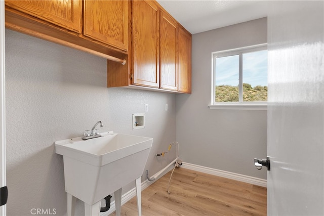 laundry area with cabinets, washer hookup, light hardwood / wood-style floors, sink, and hookup for a gas dryer