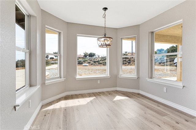 unfurnished dining area with light wood-type flooring and a notable chandelier