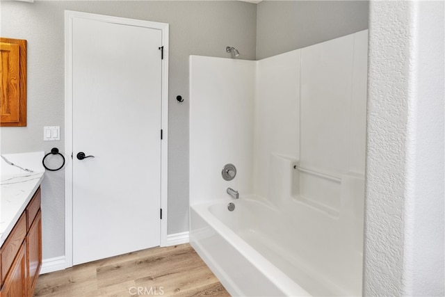 bathroom with wood-type flooring, washtub / shower combination, and vanity