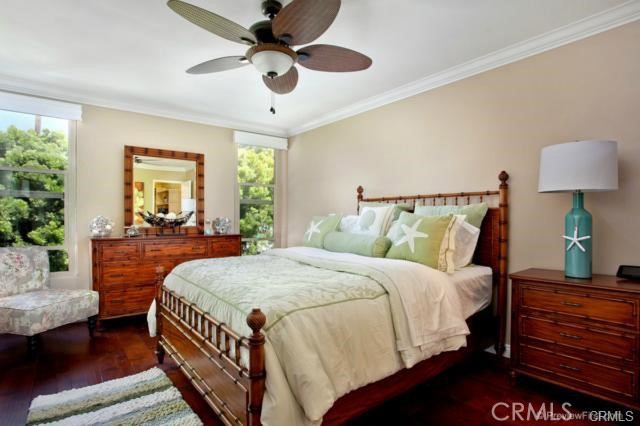 bedroom featuring dark hardwood / wood-style flooring, ceiling fan, and crown molding