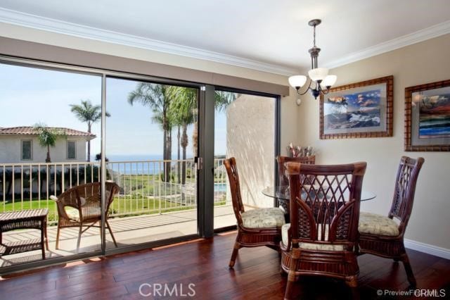 dining room with dark hardwood / wood-style flooring, a water view, crown molding, and a notable chandelier