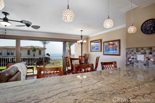 dining space with ceiling fan with notable chandelier and ornamental molding