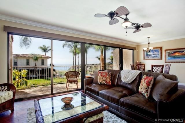 living room featuring ornamental molding, ceiling fan with notable chandelier, dark hardwood / wood-style floors, and a healthy amount of sunlight