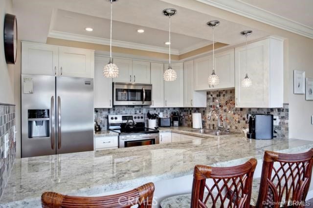 kitchen featuring white cabinetry, sink, kitchen peninsula, a kitchen bar, and appliances with stainless steel finishes